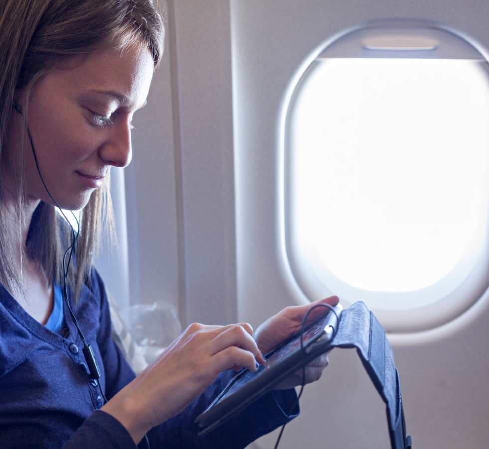 A woman is looking at her phone on an airplane.