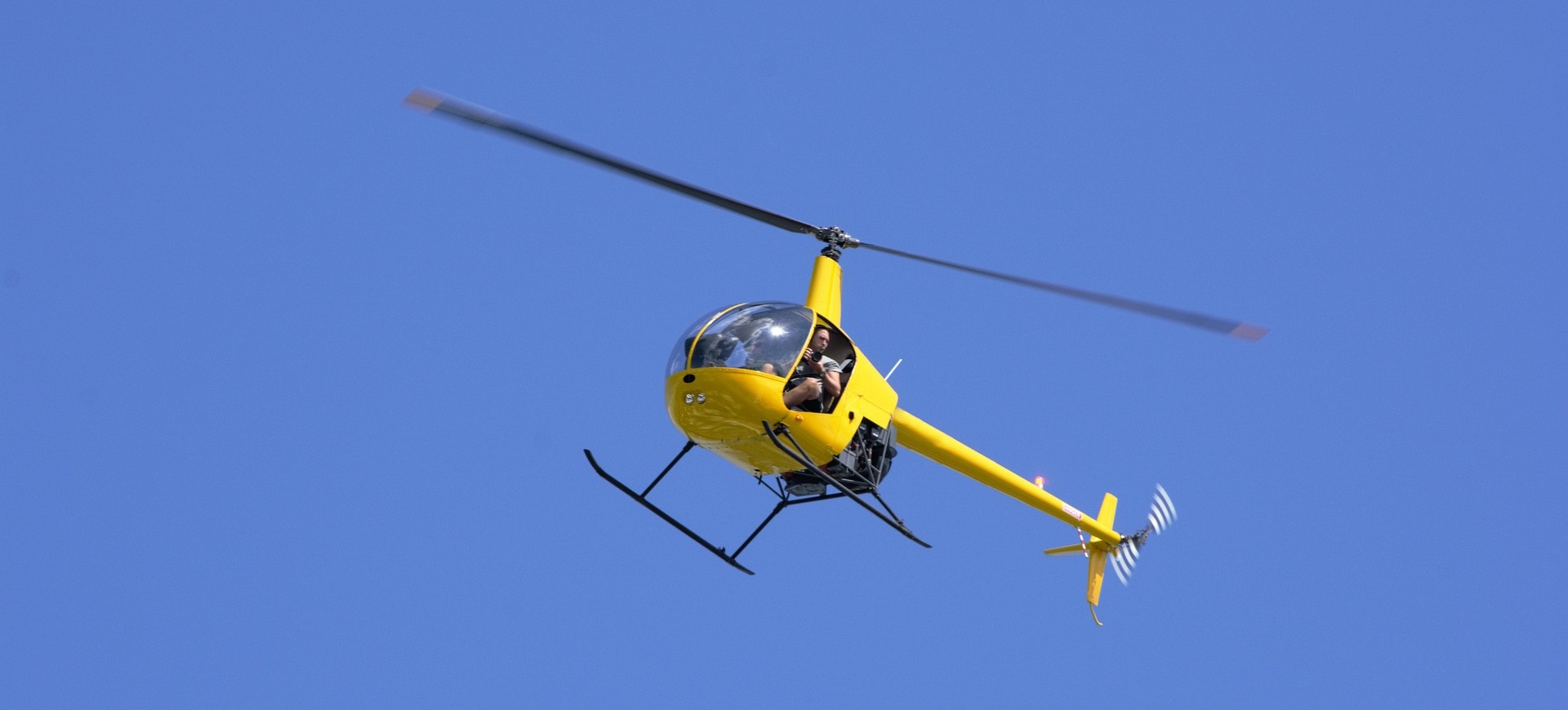 A helicopter flying in the air with a person sitting inside.