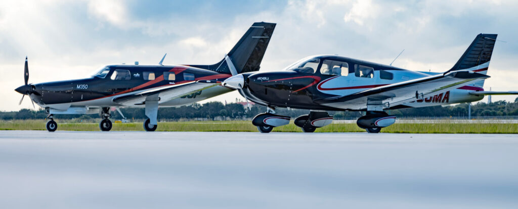 Two small airplanes are on the runway of an airport.