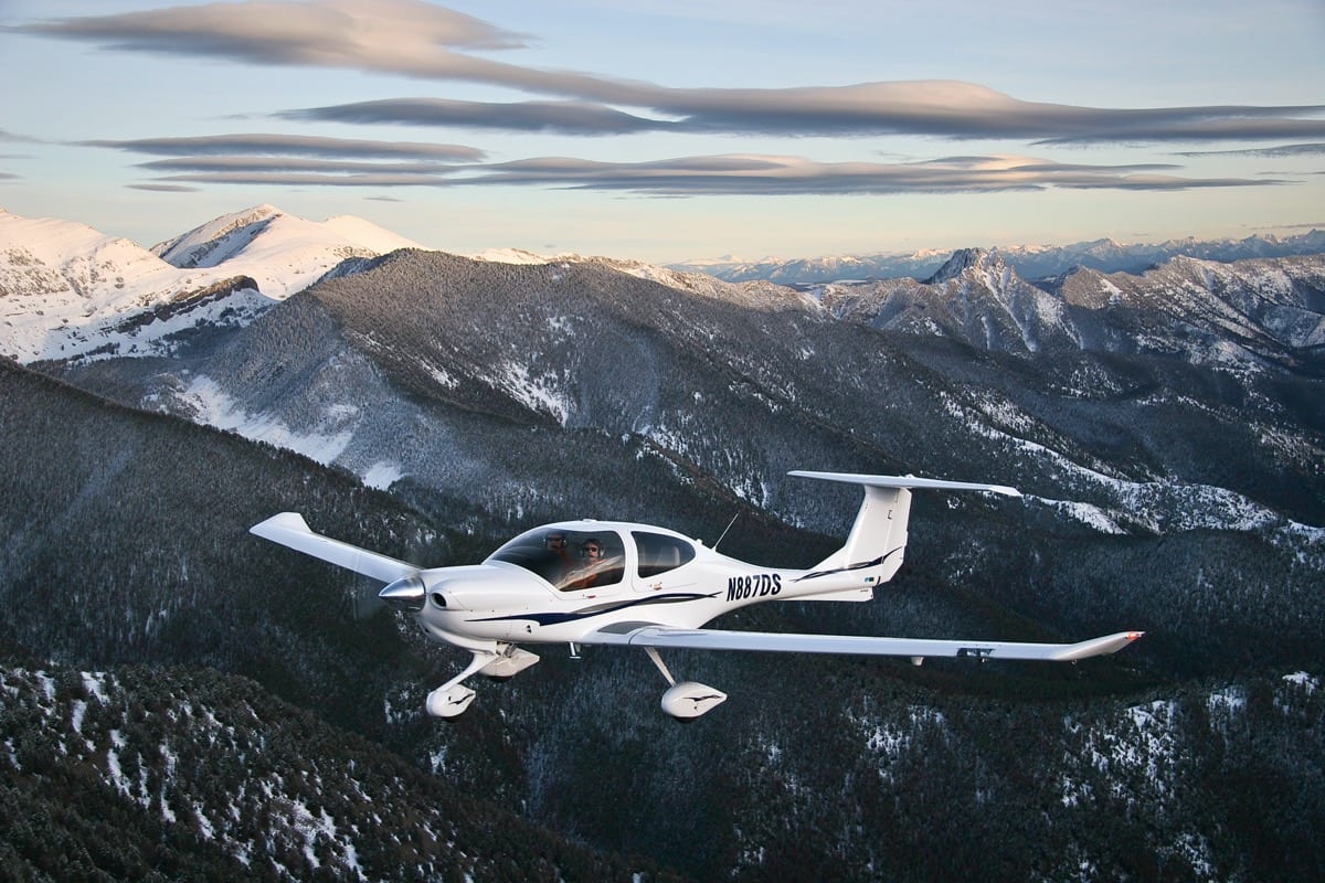 A white plane flying over the mountains in the air.